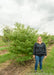 A person stands next to Pagoda Dogwood in the nursery to show height.